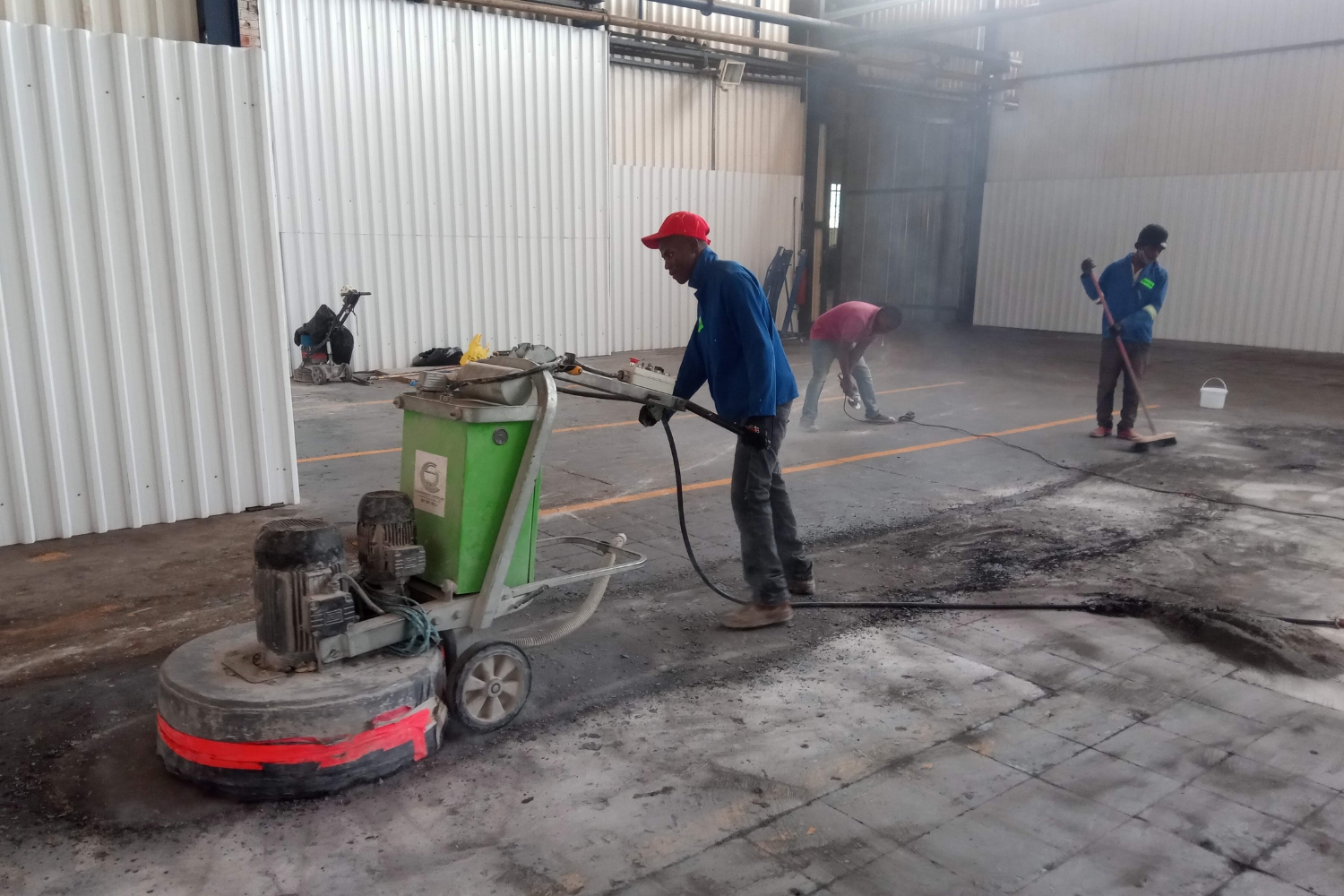 A man grinding a warehouse floor to remove contaminants before installing epoxy.
